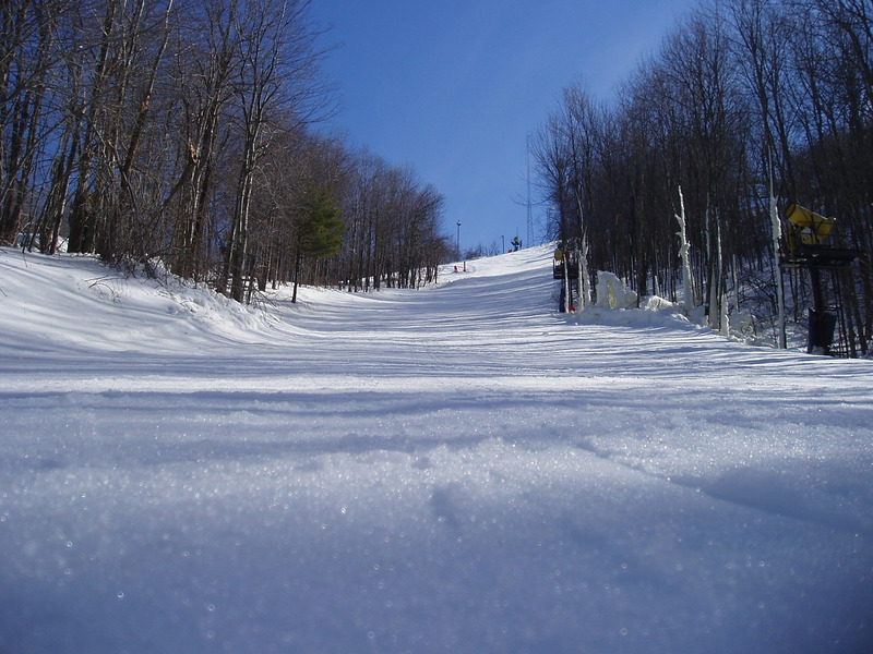 A ski slope viewed from the bottom of the run on a cloudless winter day